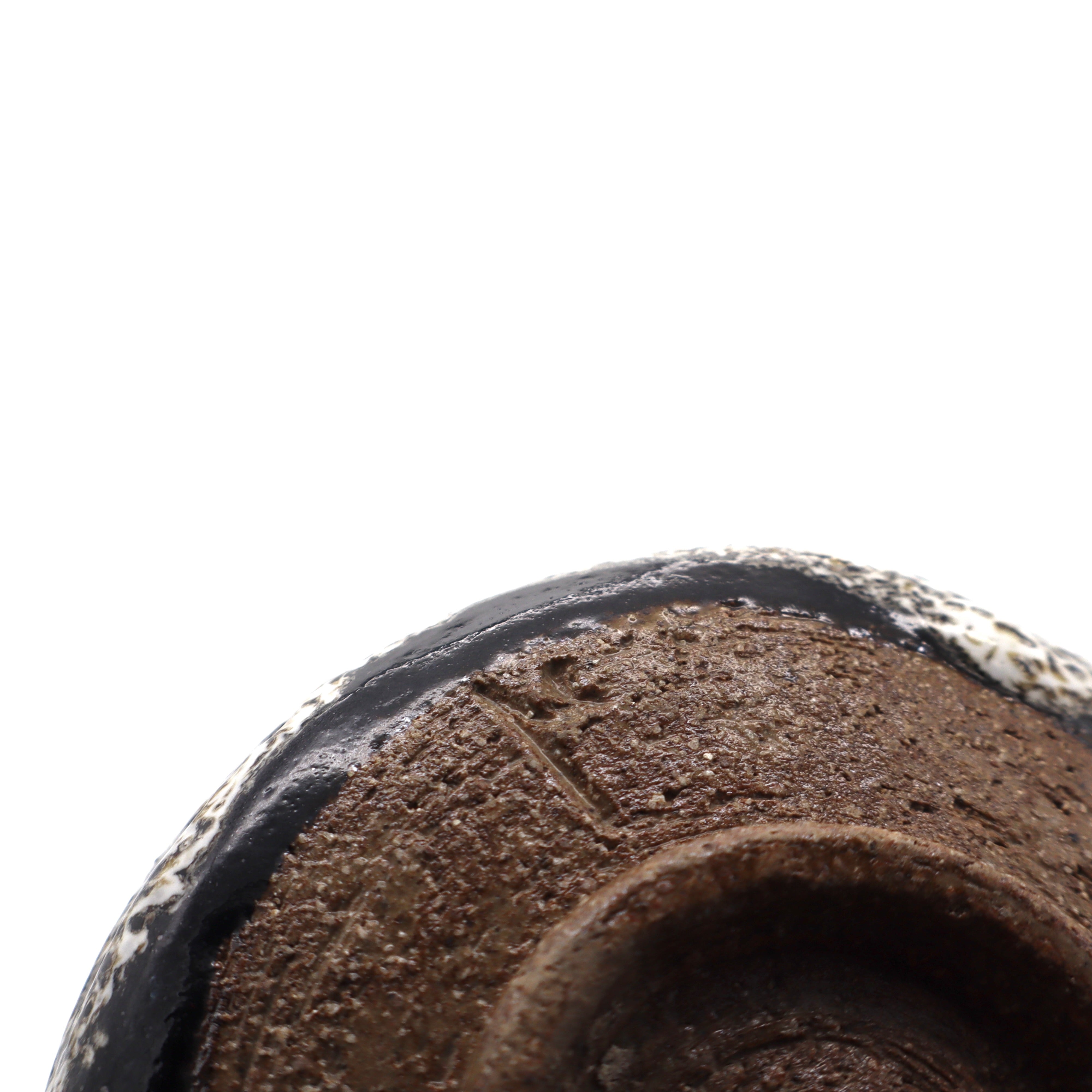 Close up of artist's signature on handcrafted Japanese matcha kutsugata chawan tea bowl from Aichi, Japan, beautiful white and black drip glaze, dark brown sandy clay, bottom view